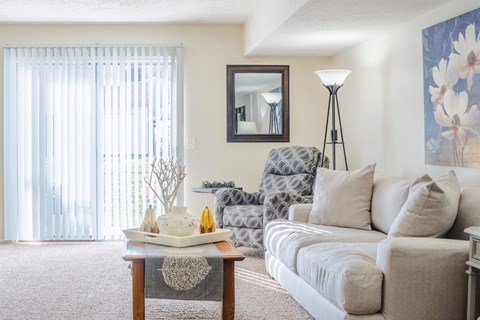 A living room with a couch, a coffee table, and a mirror on the wall.
