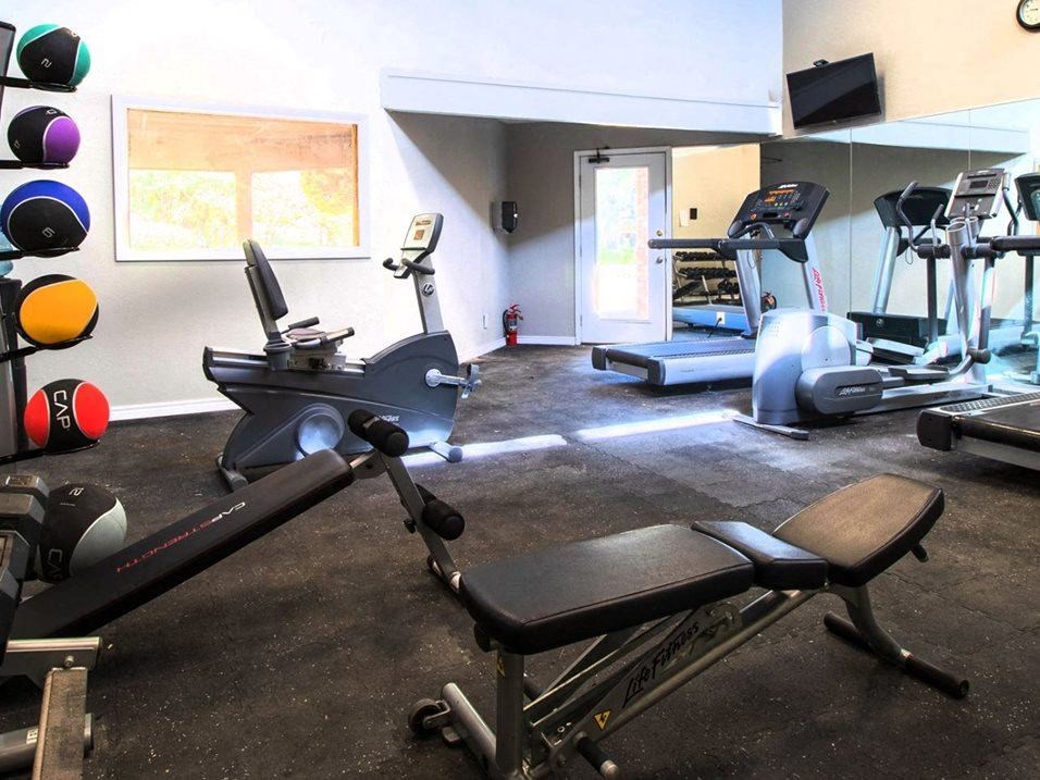 a gym with various exercise equipment in a room with a window