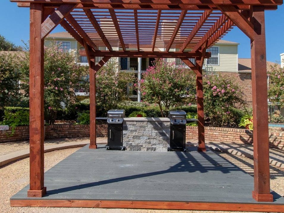 a wooden pavilion with garbage cans on a sidewalk