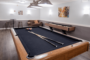 A pool table in a room with a couch and a painting on the wall.