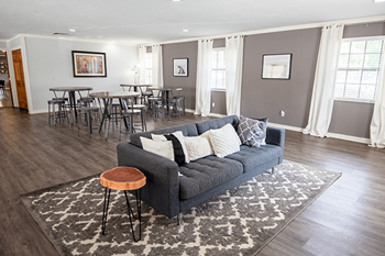 A grey couch with a wooden stool in front of it.