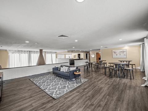 a living room with a couch and chairs and a bar with tables