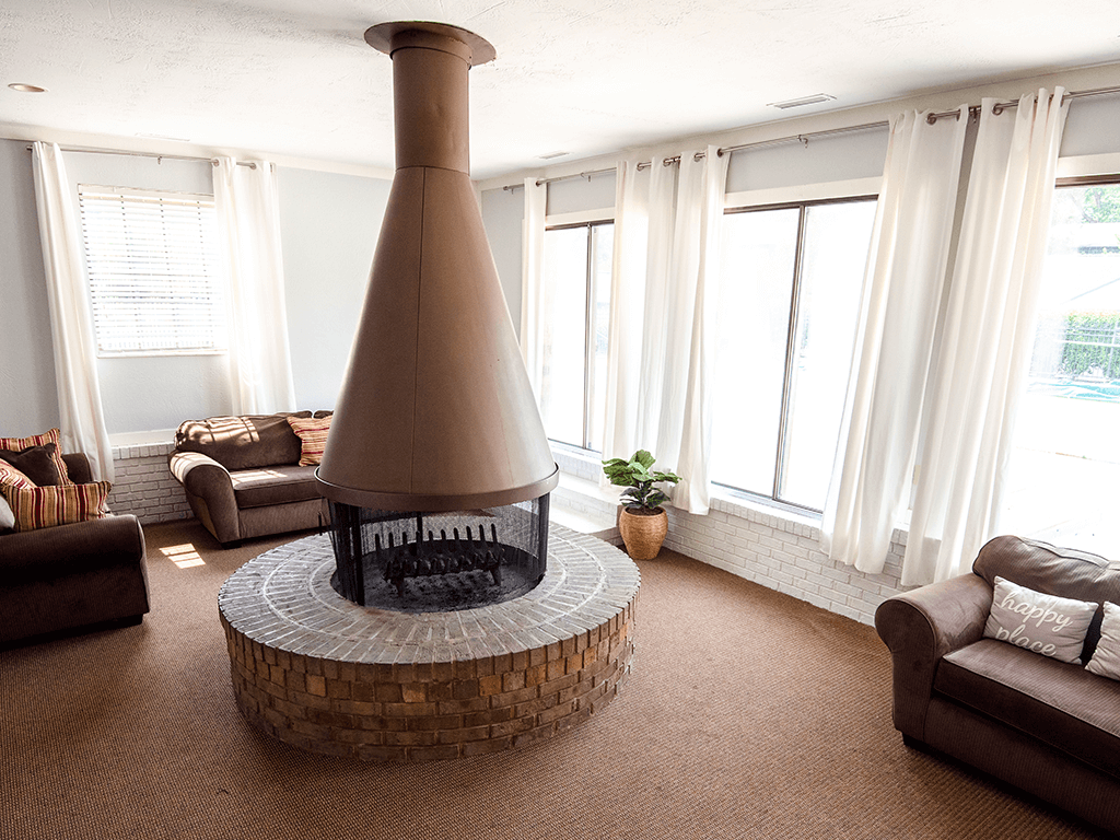 apartment clubhouse with a large fireplace and a couch.