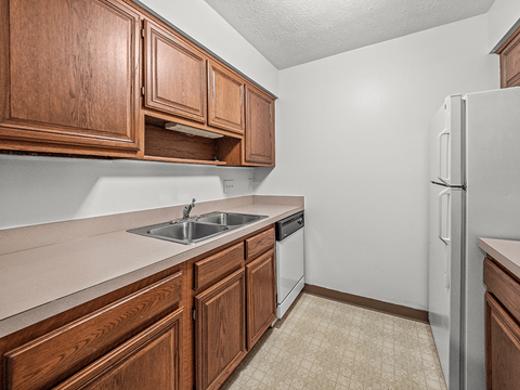 a kitchen with wooden cabinets and a sink and a refrigerator