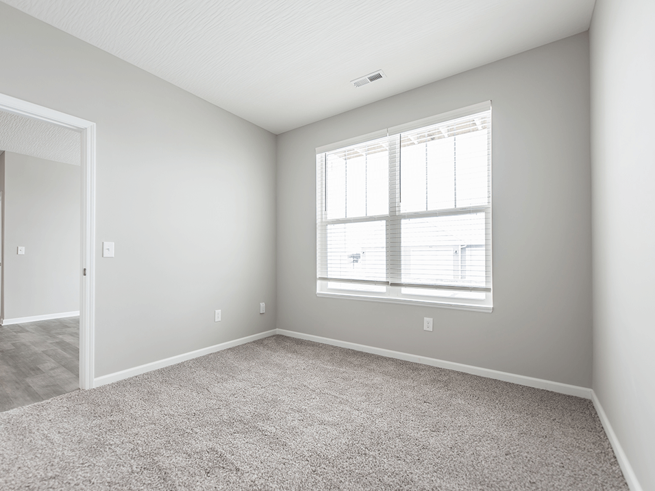 a bedroom with a large window and a carpeted floor