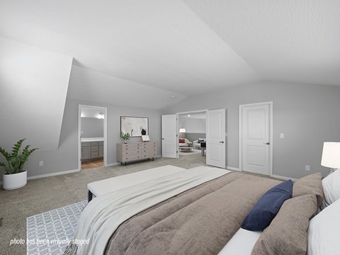 A bedroom with a large bed and a plant in the corner.