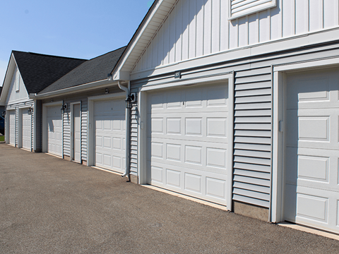 A row of white garage doors in front of a white building.