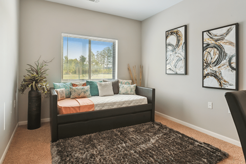 A bedroom with a large bed and two framed artworks on the wall.