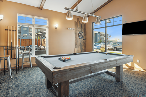 A pool table in a room with a view of the parking lot outside.
