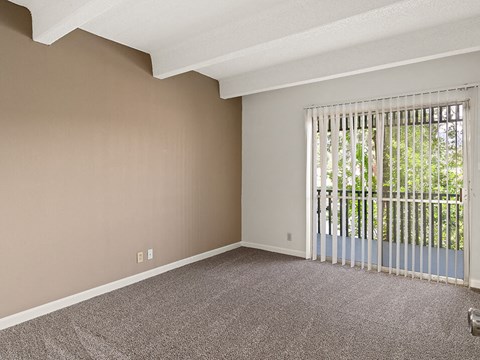 an empty living room with a large window and blinds