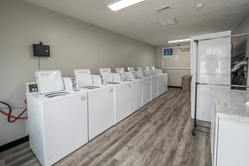 A row of white washing machines in a laundromat.