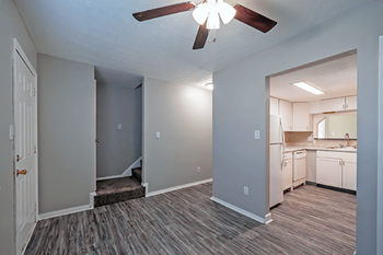 an empty living room and kitchen with a ceiling fan