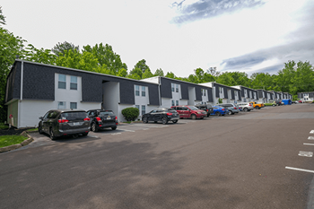 a row of apartments with cars parked in a parking lot