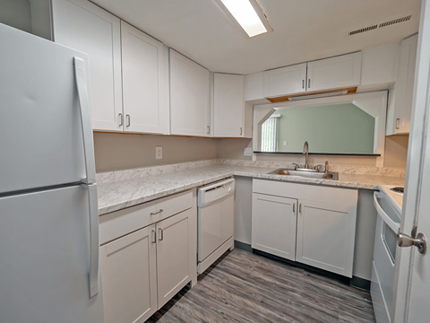 an empty kitchen with white cabinets and stainless steel appliances