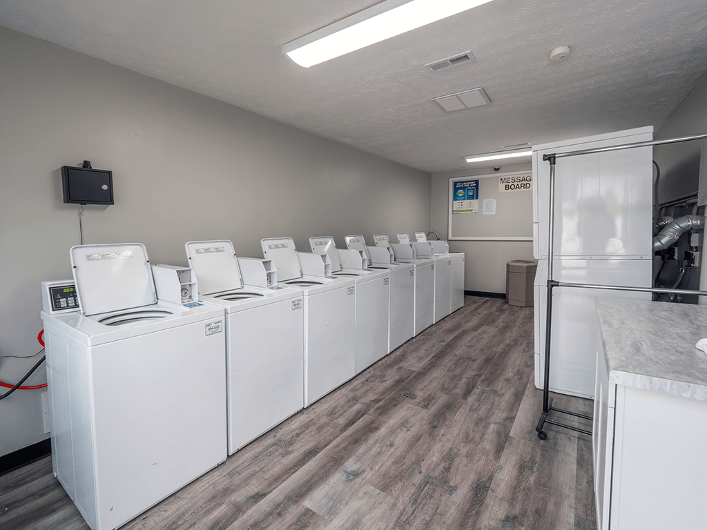 a row of washers and dryers in a room with wood flooring