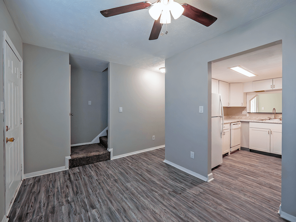 an empty living room and kitchen with a ceiling fan