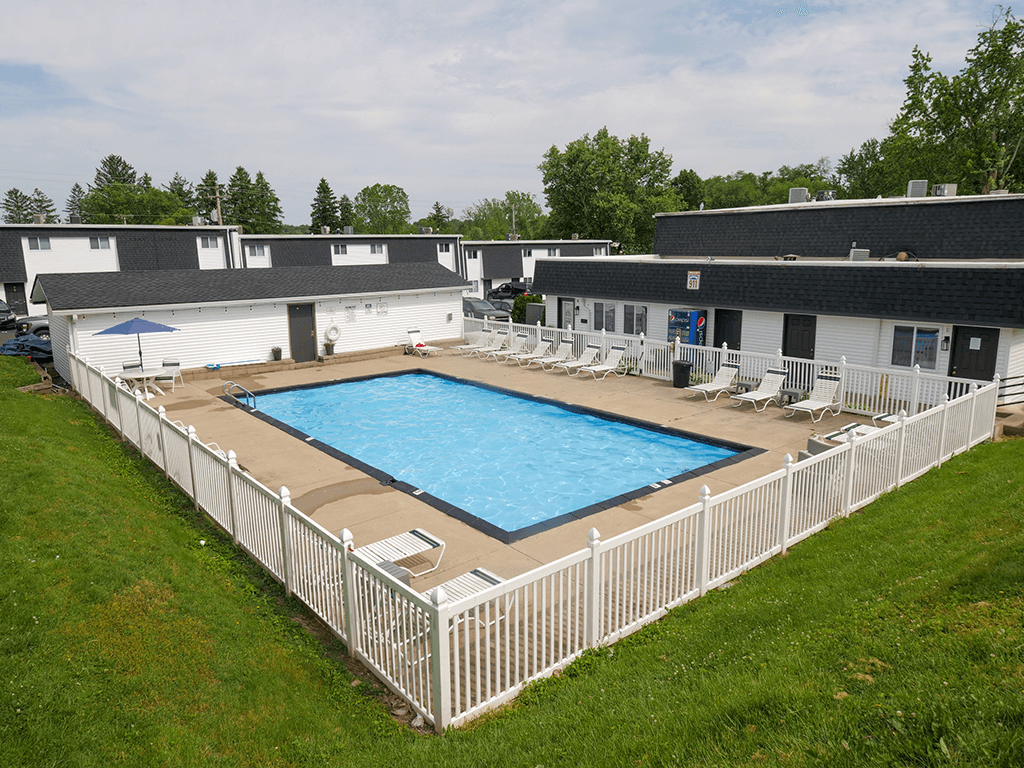 an aerial view of a resort style pool in front of a white fence