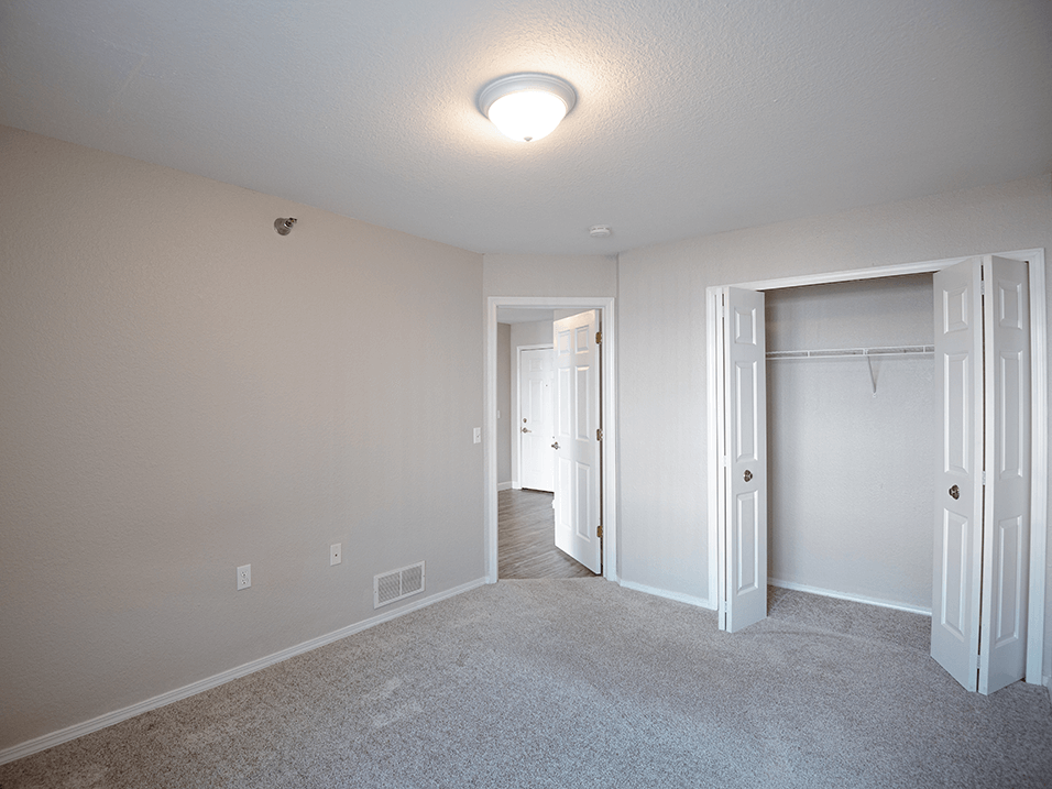 a bedroom with a carpeted floor and a closet with a white door