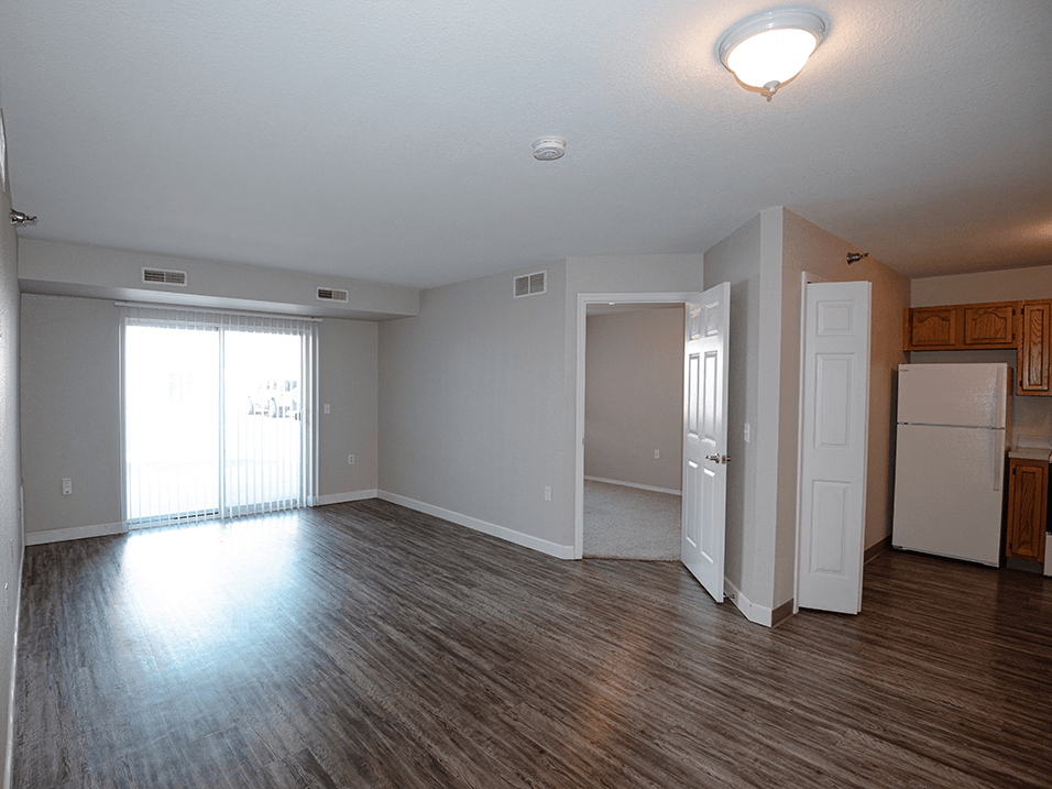 a living room with hardwood floors and a sliding glass door to a balcony