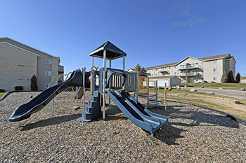 A playground with a blue slide and a wooden structure.