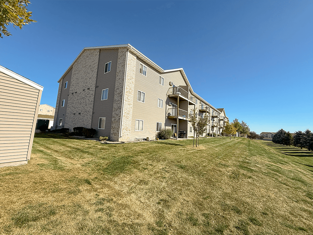 Apartment building with a grassy field in front.