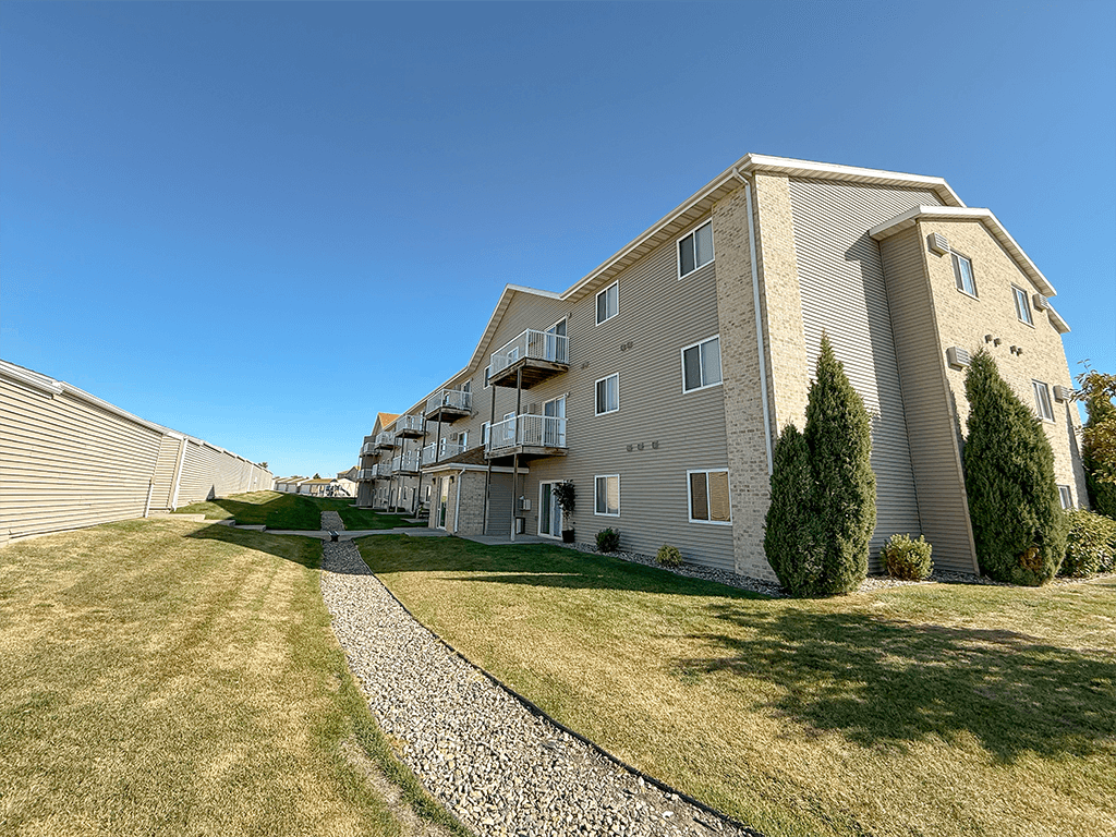 A modern apartment building with a stone pathway leading to the entrance.