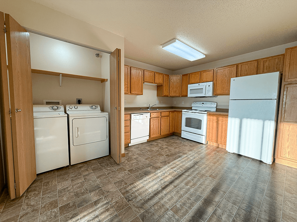 A kitchen with white appliances and wooden cabinets.