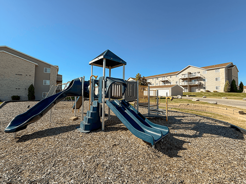 A playground with a blue slide and a wooden structure.
