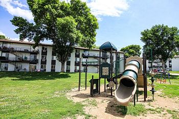 a playground with a slide and a building in the background