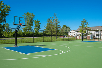 A basketball court with a blue and green surface and a basketball hoop.