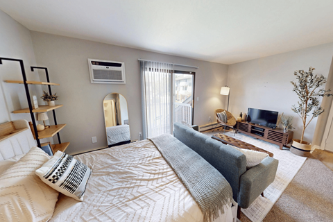 A well-lit bedroom with a large bed and a television.
