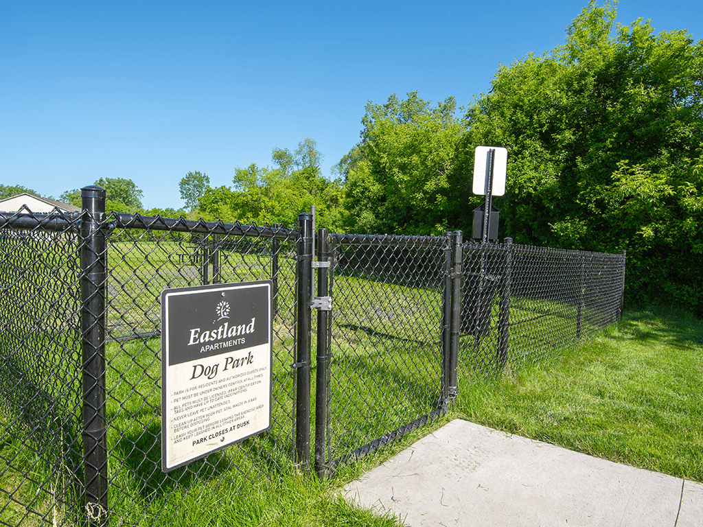 a fence with a sign on it in front of a dog park