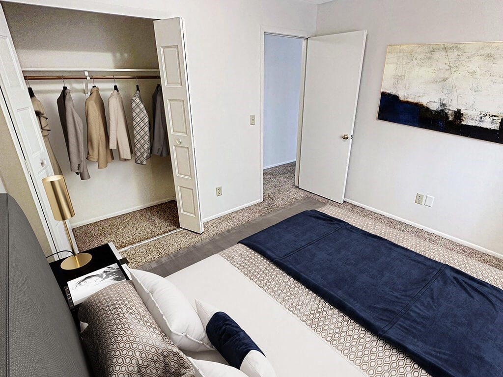 A room with a bed and a closet with clothes hanging.