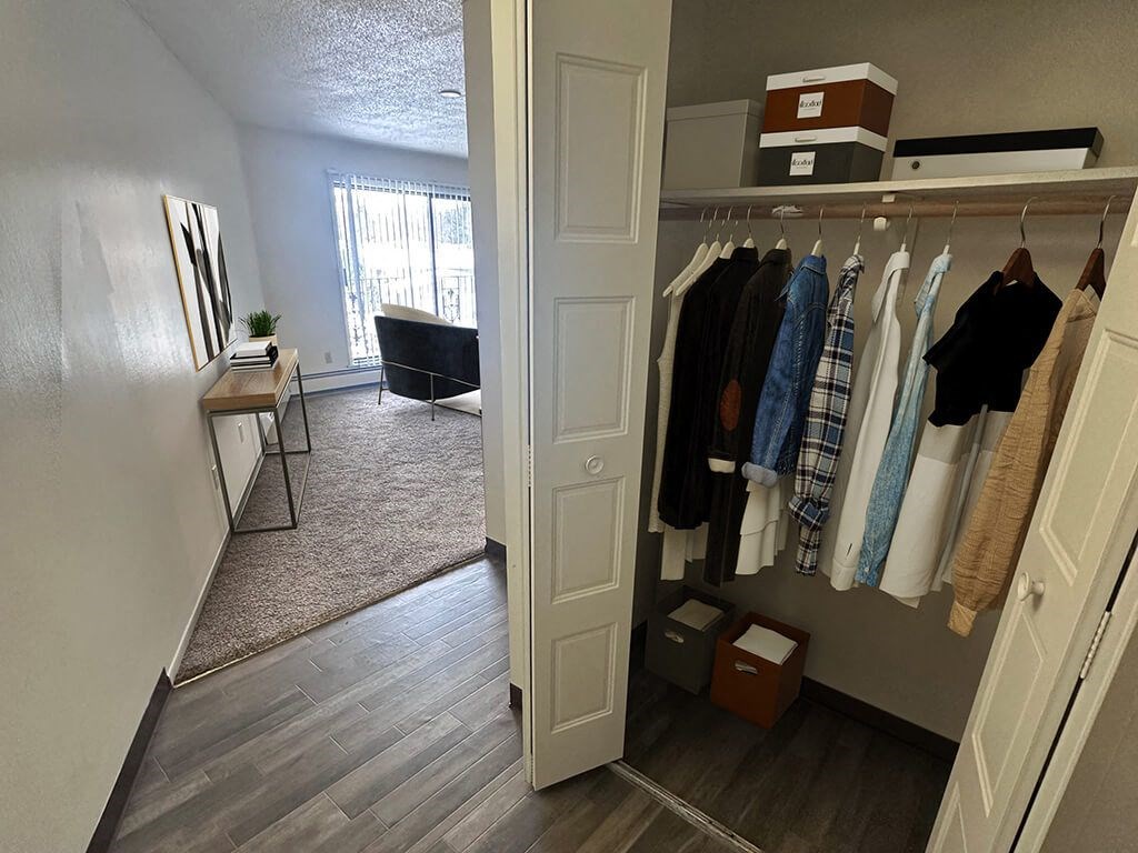 A room with a white door and a wardrobe full of clothes.