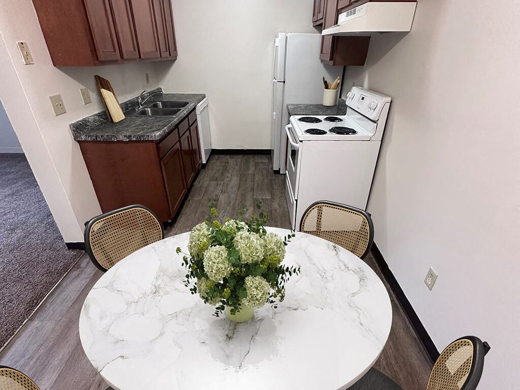 A kitchen with a white stove and a marble table with a vase of flowers on it.