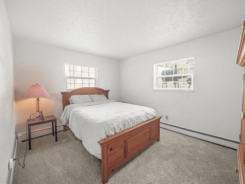A bedroom with a bed, nightstand, and window.