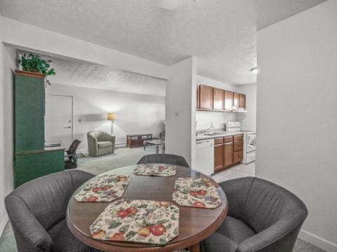 A dining room with a round table and grey chairs.