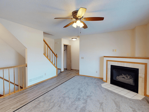 A living room with a fireplace and a ceiling fan.