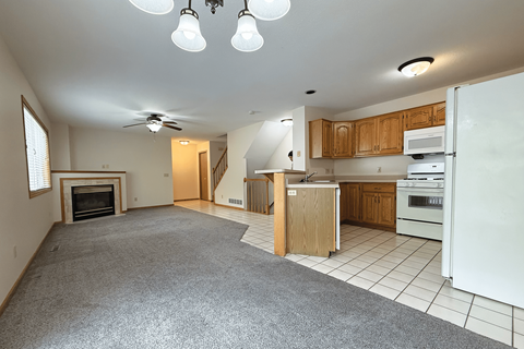 A spacious kitchen and living room with a fireplace and a ceiling fan.