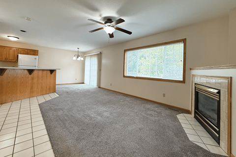 A spacious living room with a ceiling fan and a fireplace.