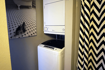 A white washing machine sits in a small bathroom.