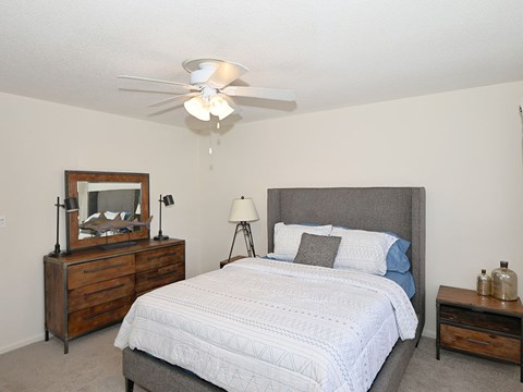 A bedroom with a bed, nightstand, and a dresser with a mirror.