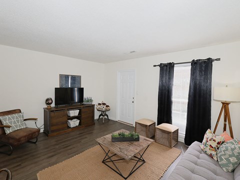 A living room with a grey couch, a wooden coffee table, and a television on a cabinet.