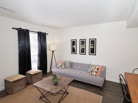 A living room with a grey couch, a wooden coffee table, and a black chair.
