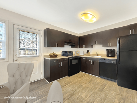 A kitchen with black appliances and wooden floors.