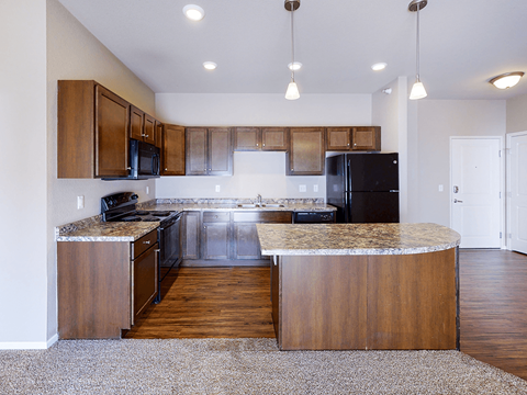 A kitchen with wooden cabinets and a black refrigerator.