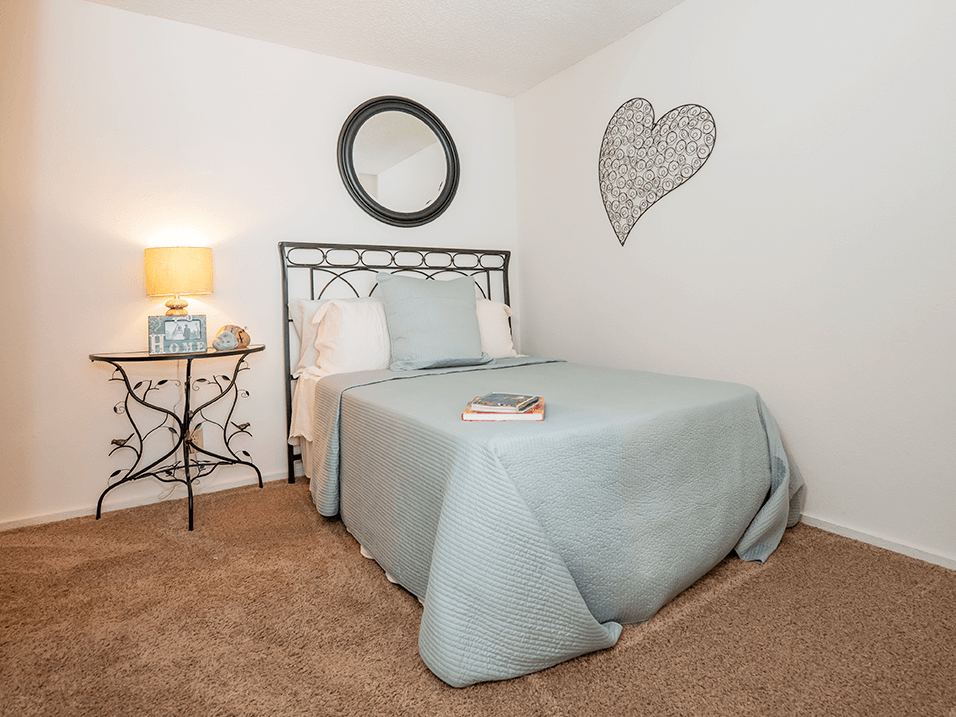 a bedroom with a bed and a nightstand with a lamp