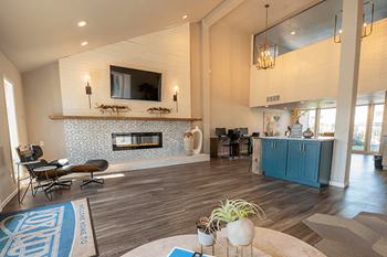 a living room with a fireplace and a kitchen in the background