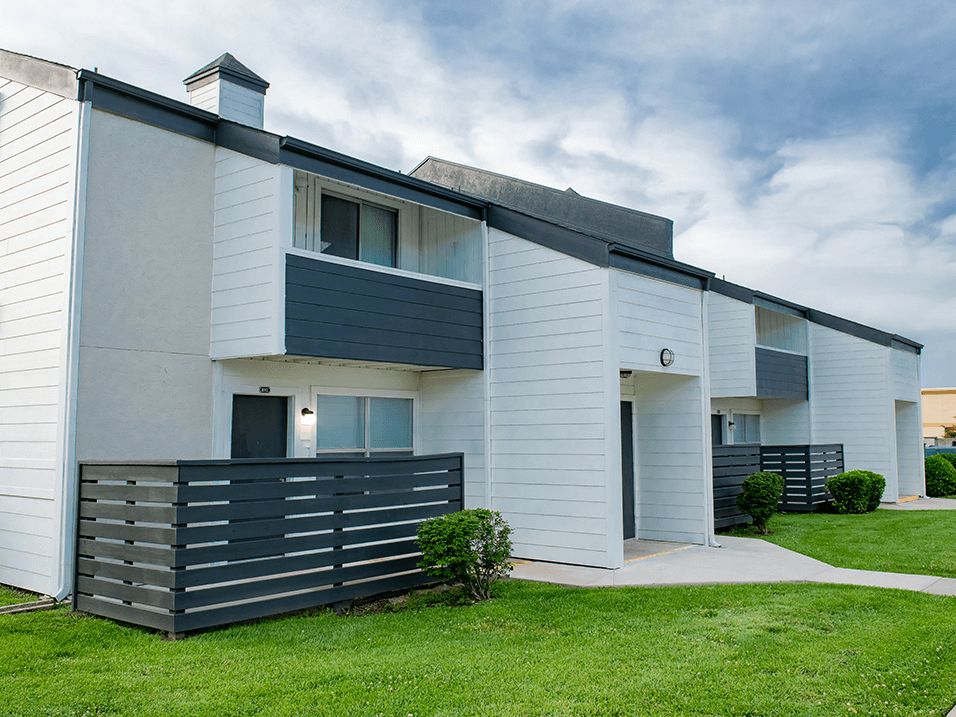 a picture of a white apartment building with a black fence