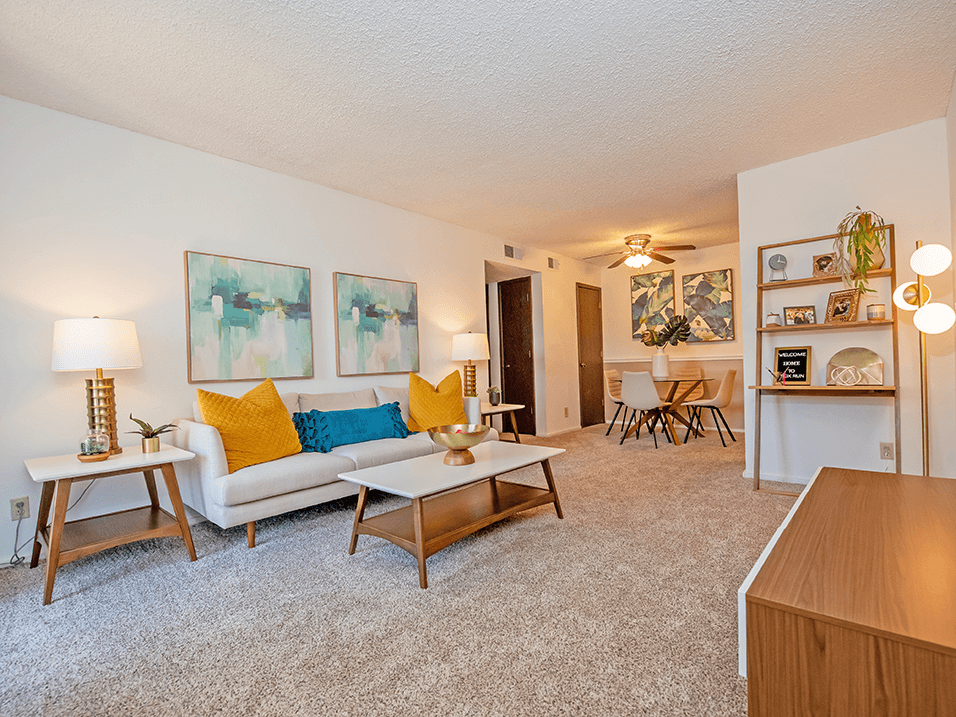 a living room with a white couch and yellow and blue pillows